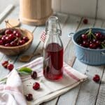 Homemade cherry vinegar in glass jar with cherries and vinegar ingredients